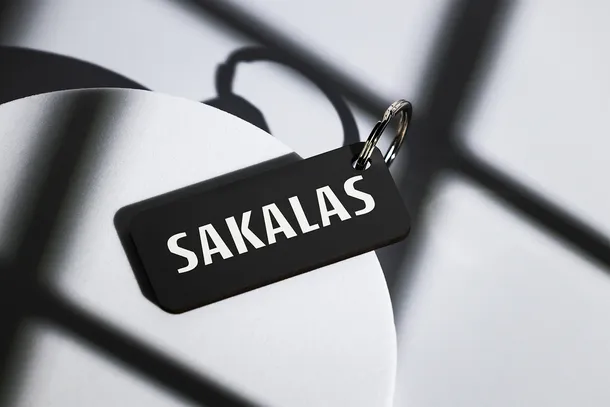 Black Sakalas branded luggage tag with white text on suitcase handle